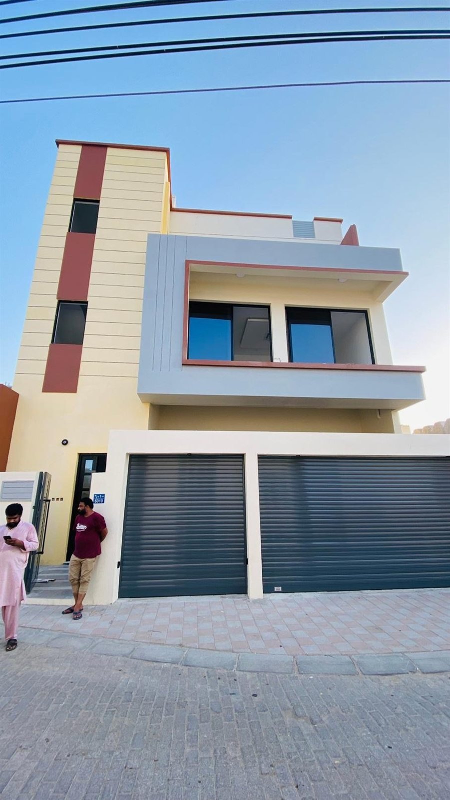Villa with orange and red painted panels and garages